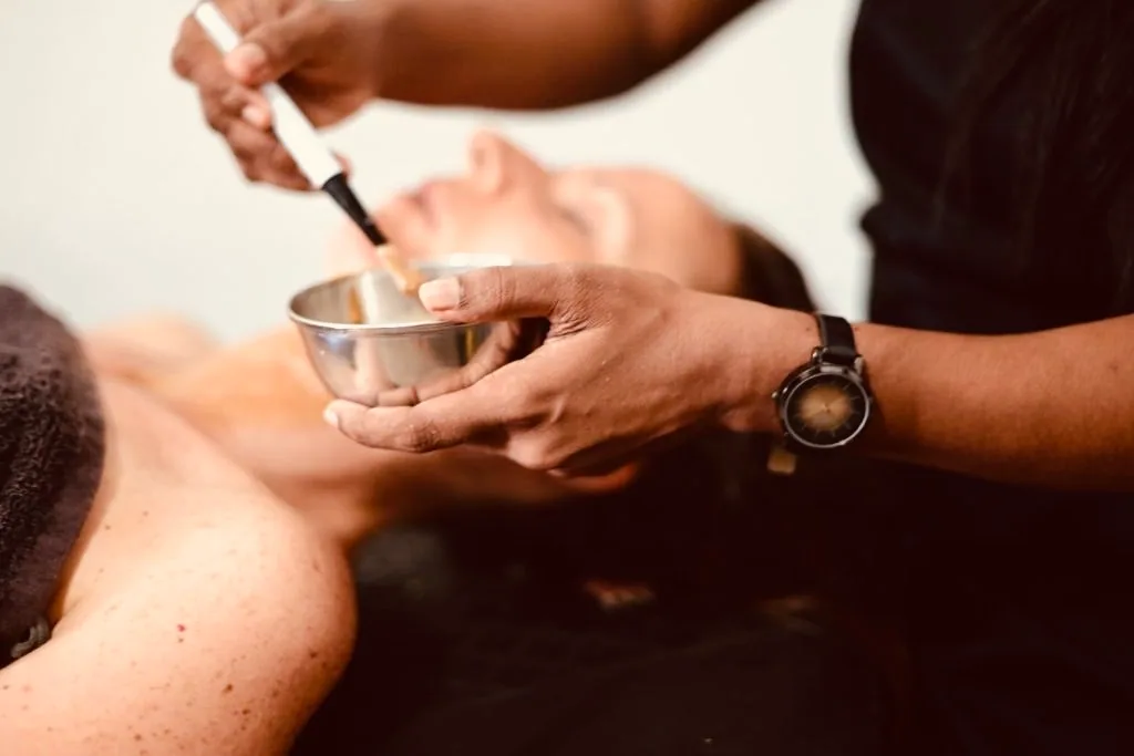 Ayurvedic spa therapist applying a treatment during a massage